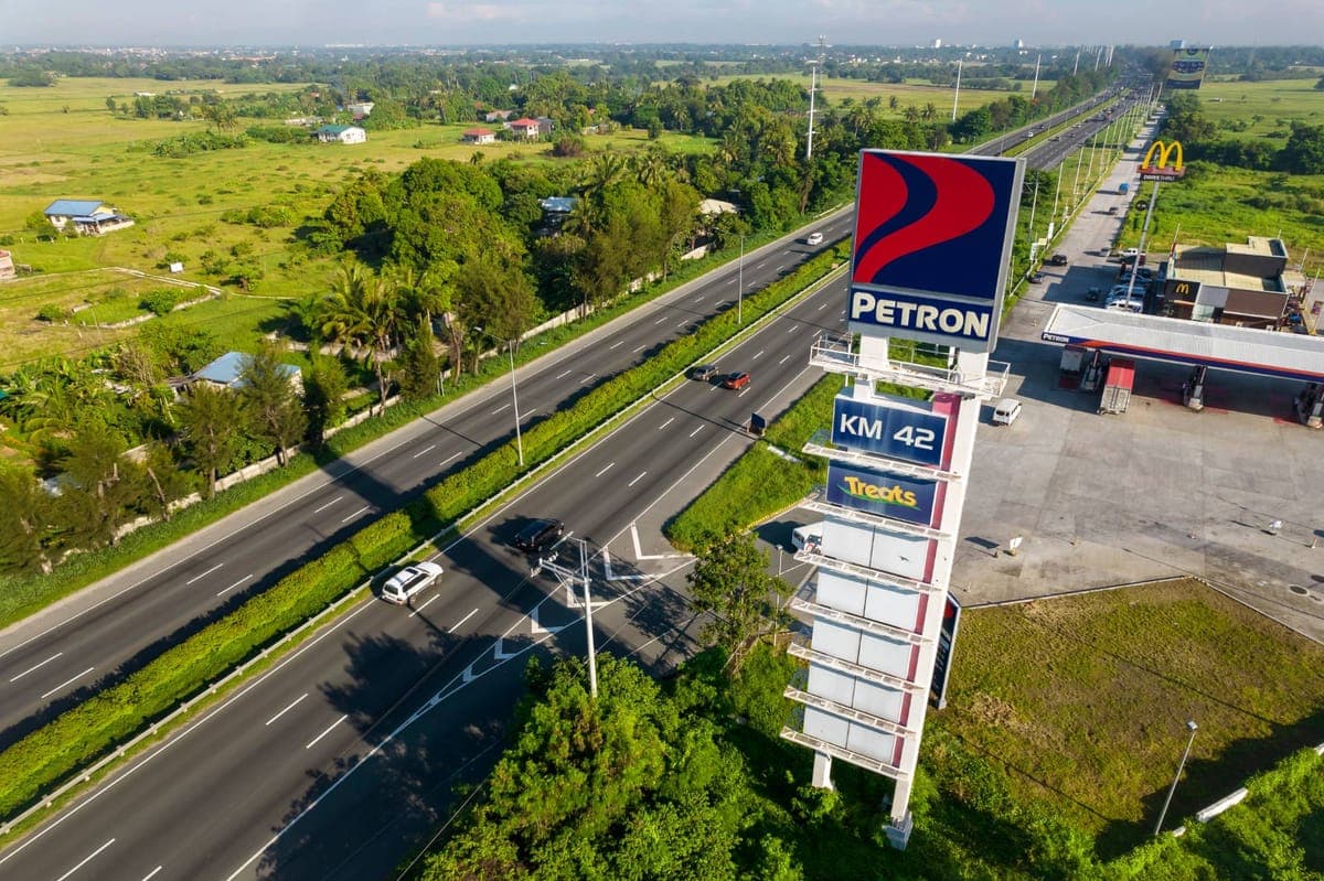 Aerial view of a divided highway passing a petrol station, with fields and trees alongside