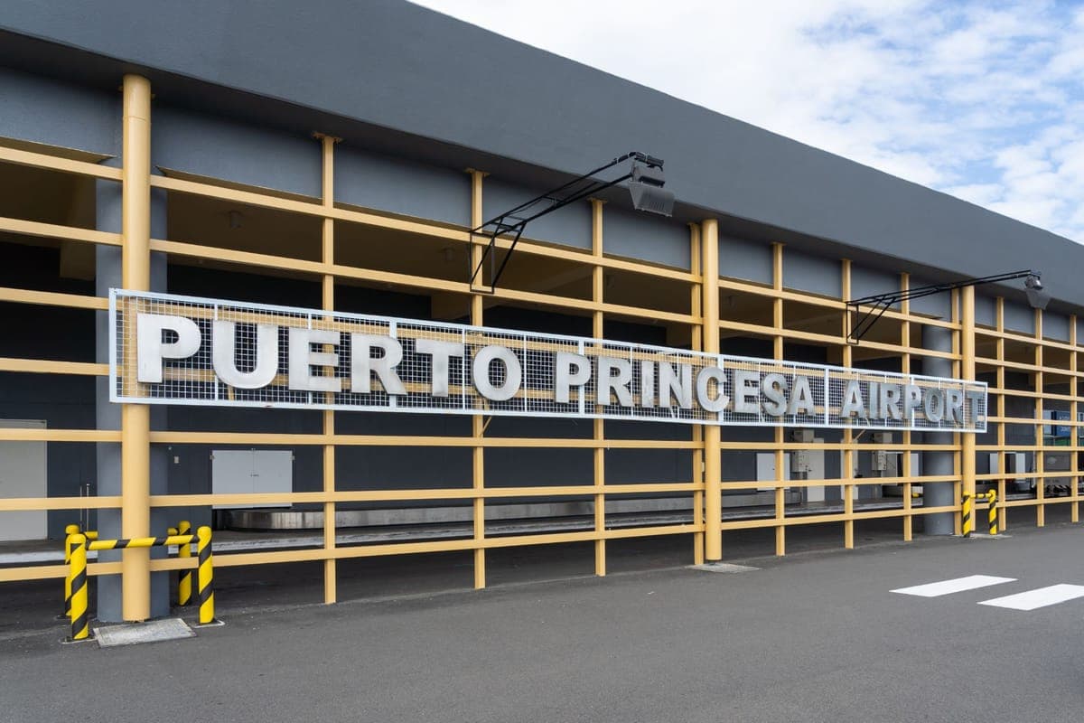 Puerto Princesa Airport sign on the grey terminal building behind yellow railings